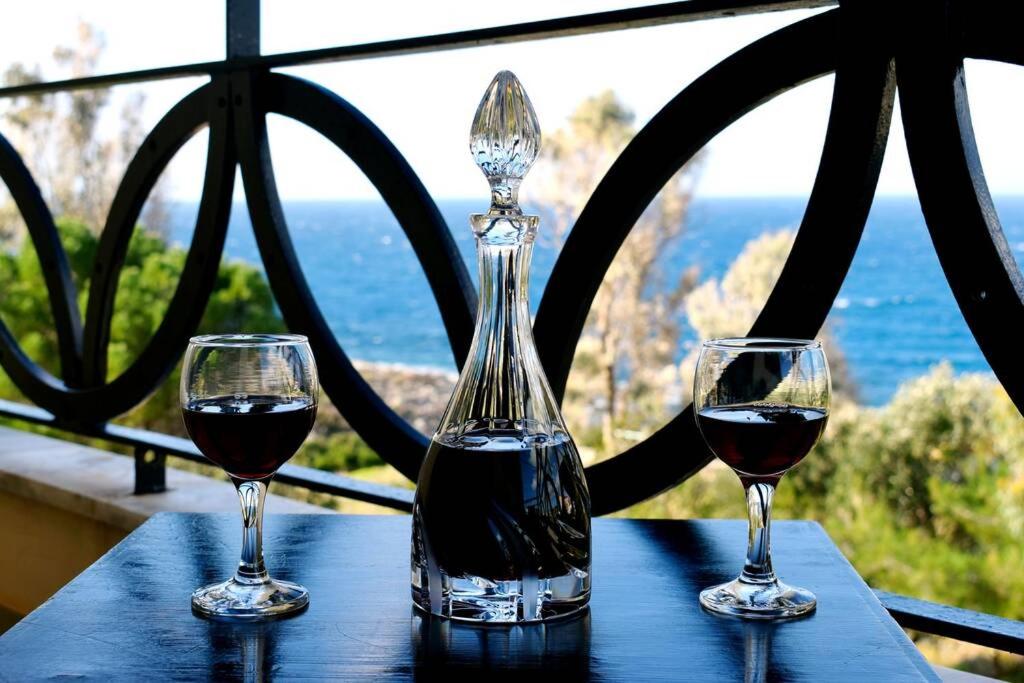 zwei Gläser Rotwein auf einem Tisch mit Fenster in der Unterkunft Magnificent sea view,clean and bright apartments in Kalathas