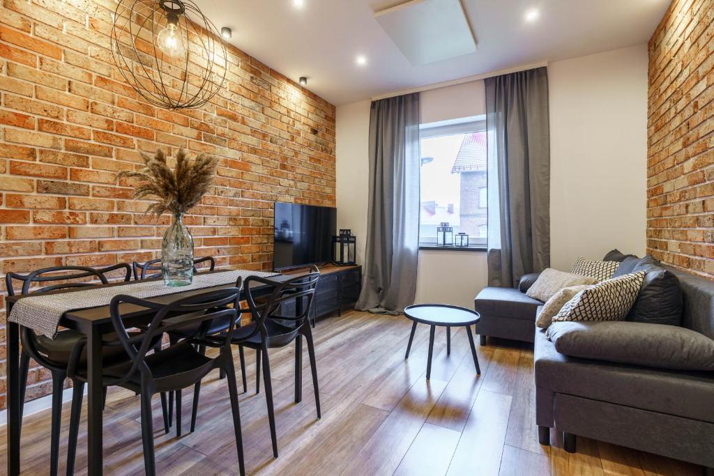 a living room with a brick wall and a table and chairs at Loftowy apartament w sercu Śląska in Ruda Śląska