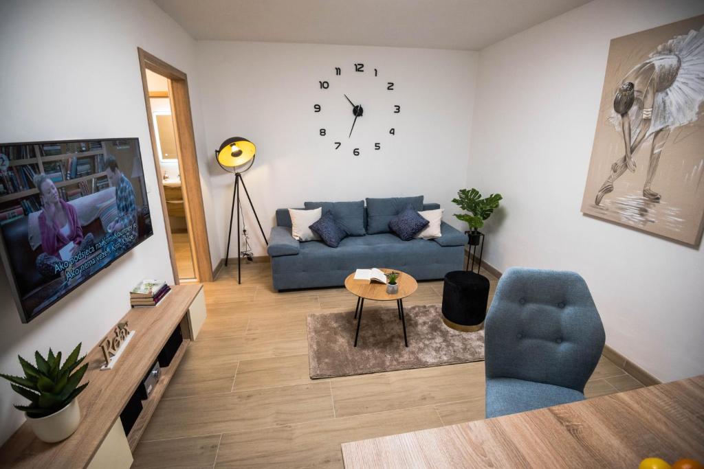 sala de estar con sofá azul y reloj en N & D, en Šibenik