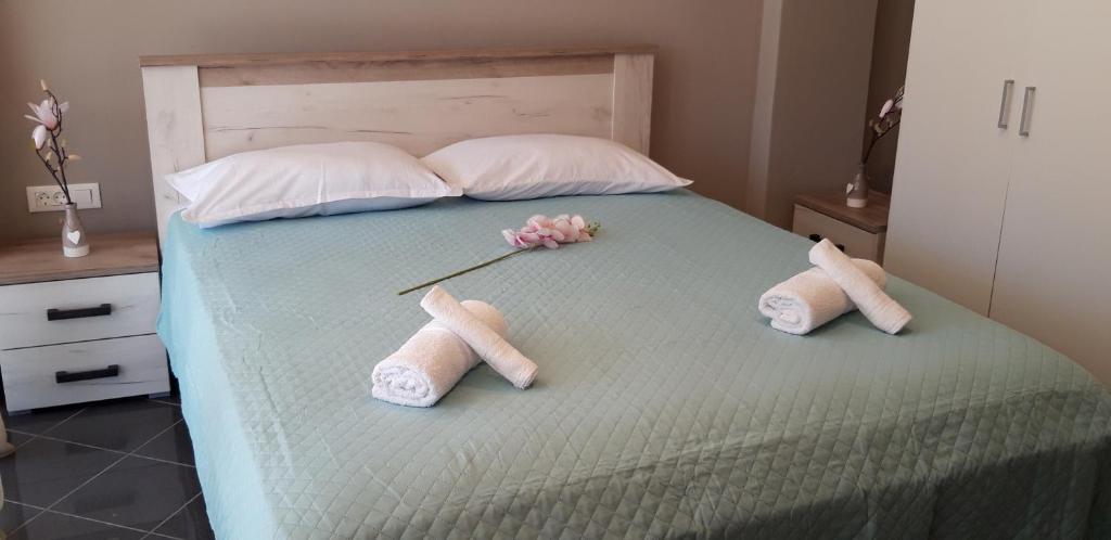 een bed met twee paar slippers en bloemen erop bij Sp+P apartment in Alepou