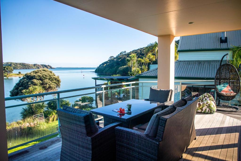 een veranda met een tafel en stoelen en uitzicht op het water bij Soul Retreat - Cable Bay Holiday Home in Cable Bay