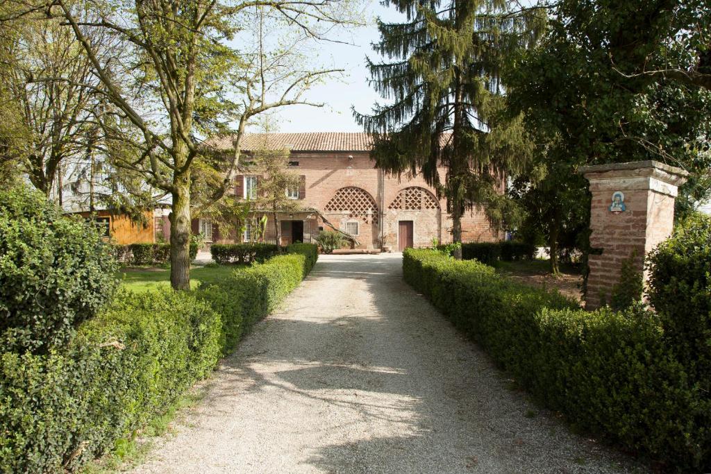 un vialetto che conduce a una casa con un edificio di Agriturismo Dosso al Porto a Rolo