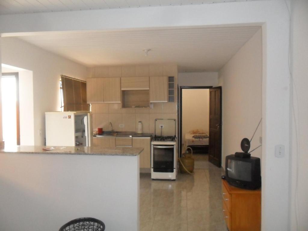 a kitchen with white appliances and a tv in it at Assel Loft Xaxim Empreiteiras in Curitiba