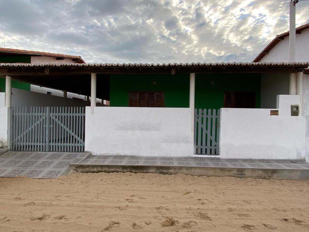 ein grünes und weißes Haus mit einem weißen Zaun in der Unterkunft Casa em Galinhos/RN in Galinhos
