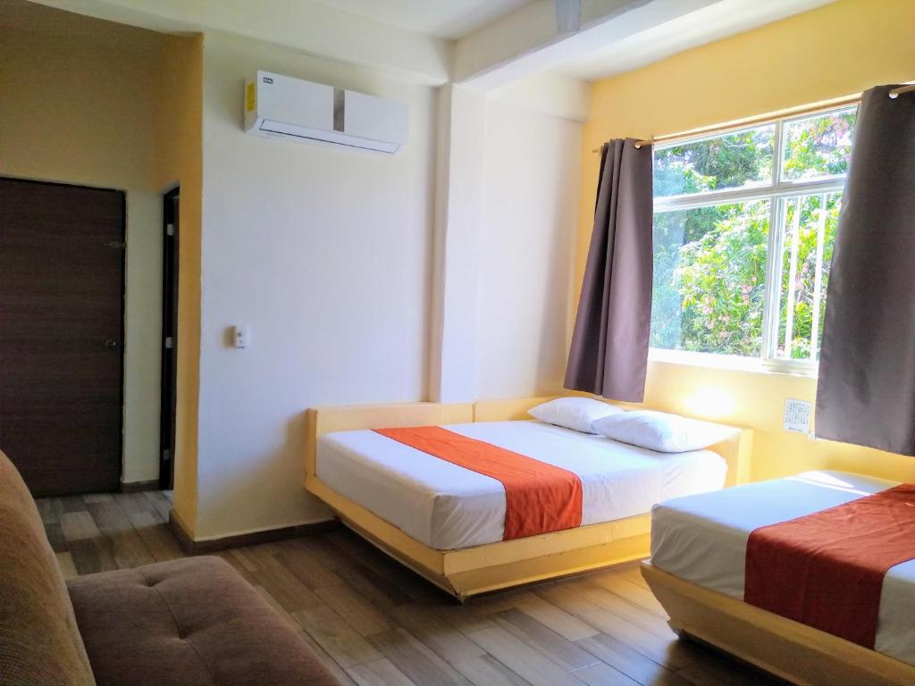 1 dormitorio con 2 camas y ventana en Los Bungalitos en Rincon de Guayabitos