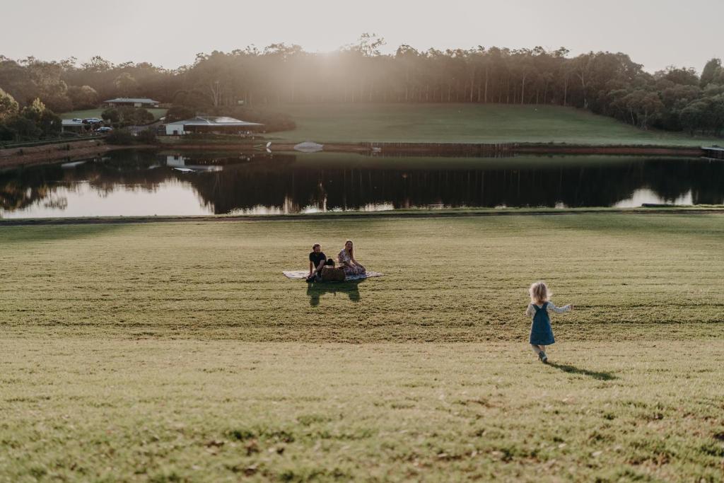 a little girl standing in a field with two people at Tanah Marah in Margaret River Town