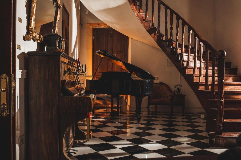 ein Klavier in einem Zimmer mit kariertem Boden in der Unterkunft La Casa del General Hotel Boutique in Parral