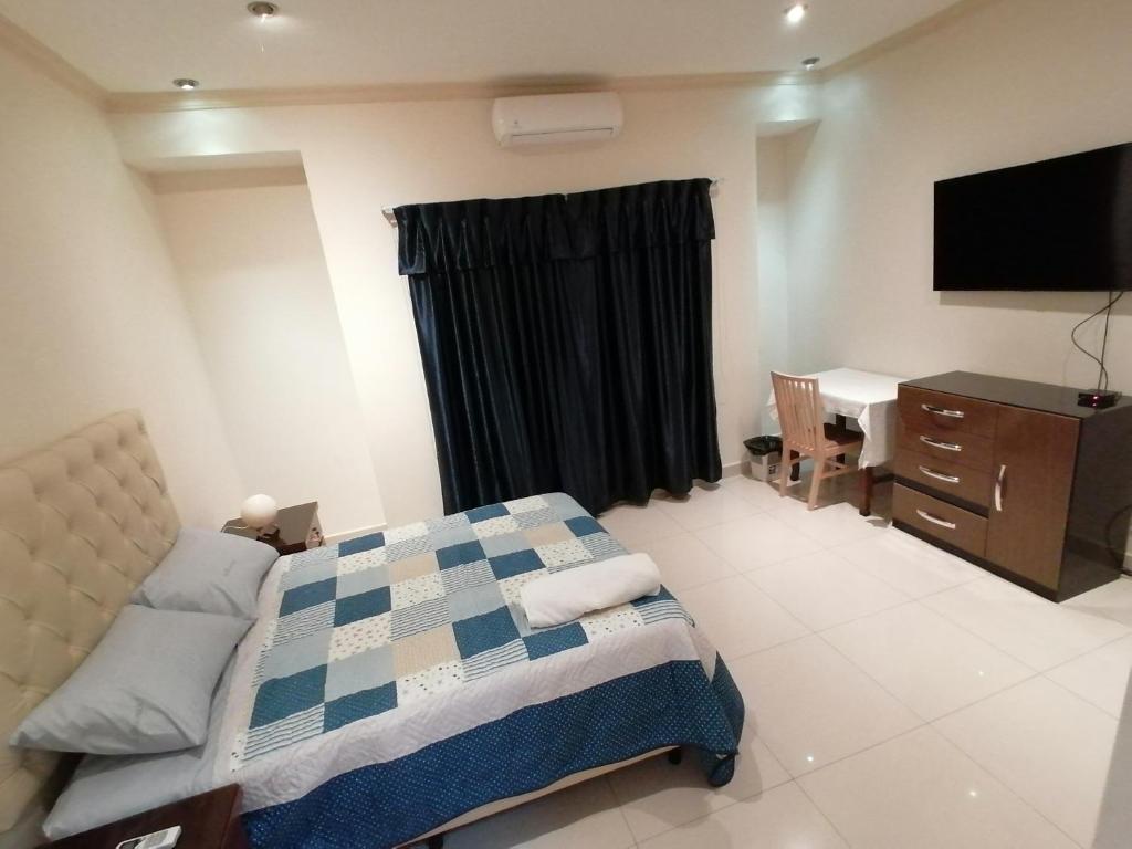 a bedroom with a bed and a desk and a television at El Prado in Santa Cruz de la Sierra