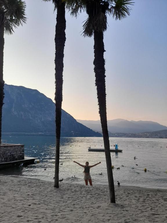 una mujer parada entre dos palmeras en una playa en Anna's Home ☆, en Campione dʼItalia