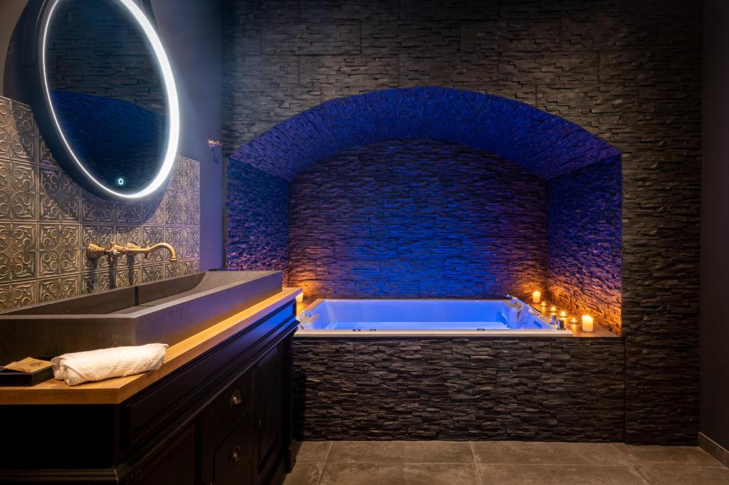 La salle de bains est pourvue d'une grande baignoire avec un mur en pierre. dans l'établissement La Bastide du Rocher Boutique Hôtel & Spa, à Roquebrune-sur Argens