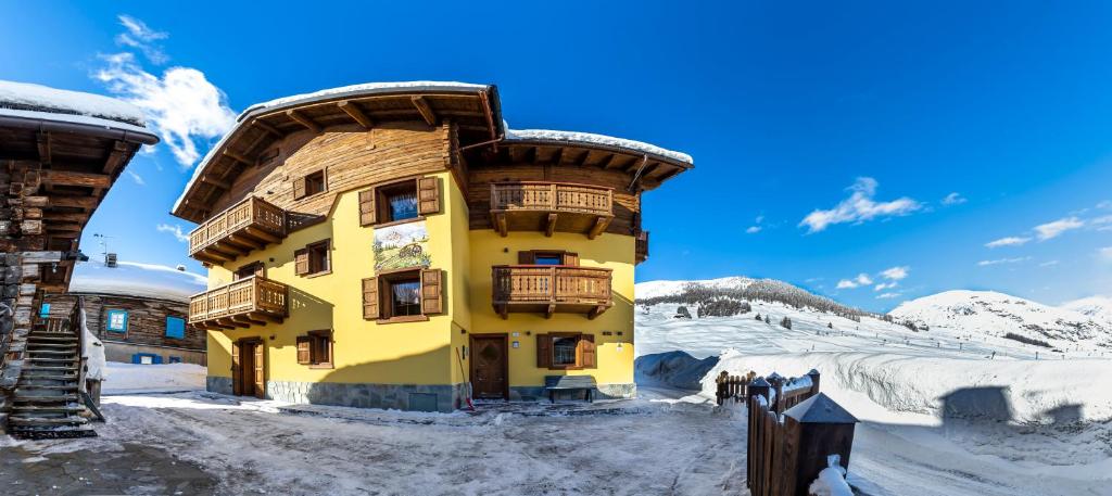 a large yellow building in the snow with snow at Baita Nicoló in Livigno