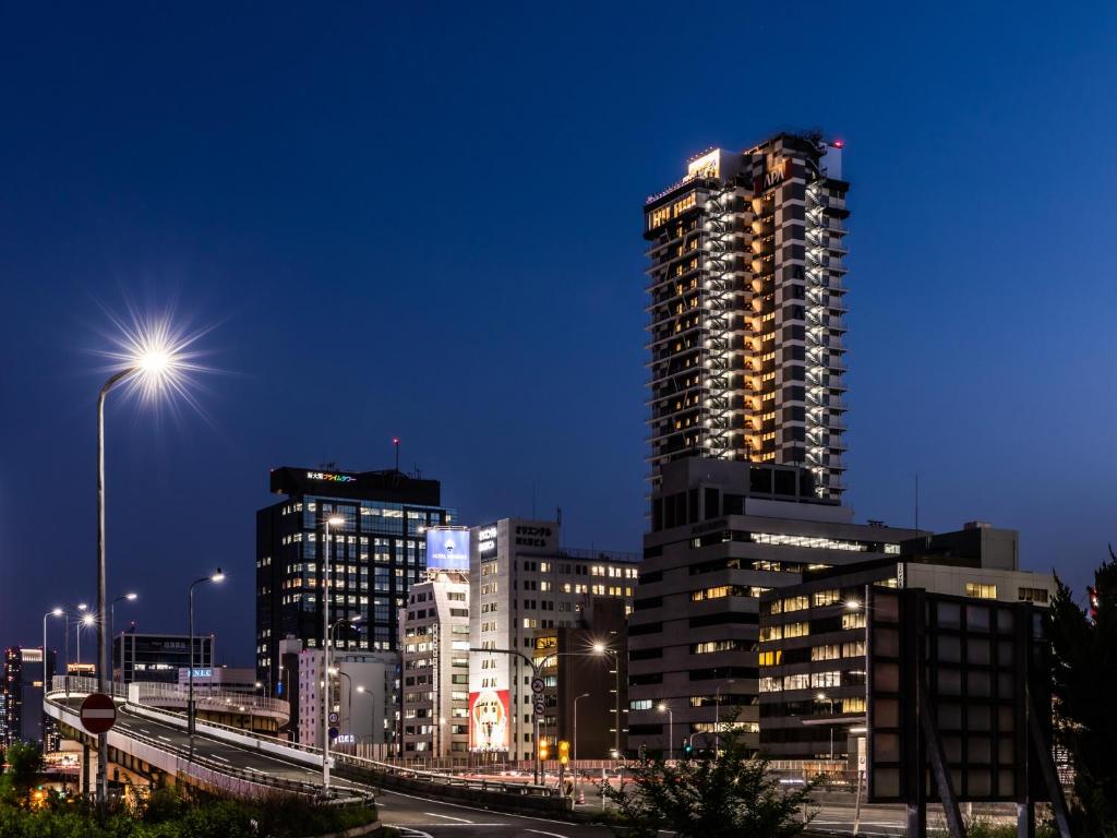大阪市にあるアパホテル〈新大阪駅タワー〉の高層ビルのある夜の街並み