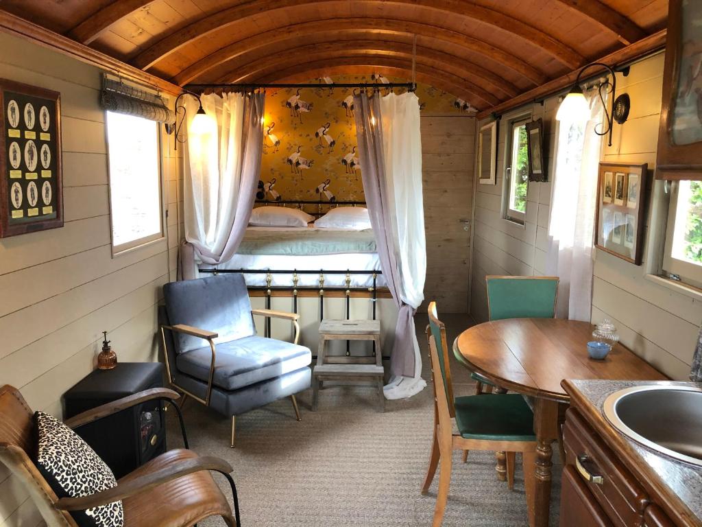 Cette petite chambre comprend un lit, une table et une chaise. dans l'établissement Roulotte à Honfleur, à Honfleur