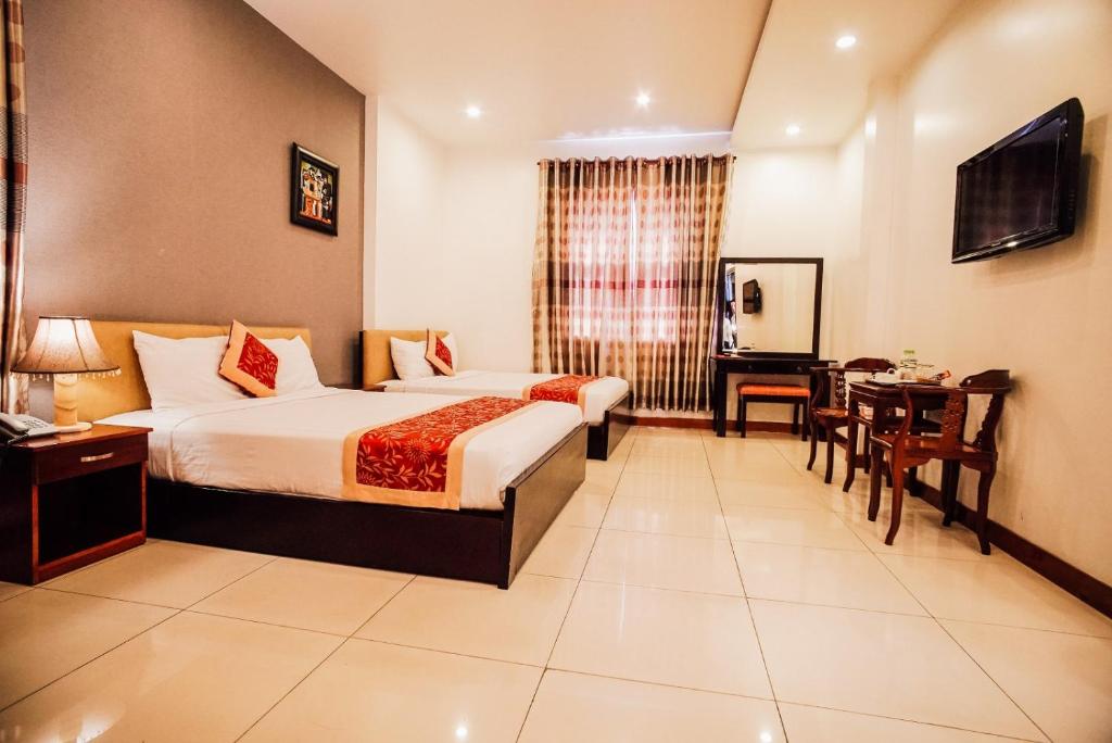 a hotel room with a bed and a desk and a table at Sunflowers Hotel Airport in Ho Chi Minh City