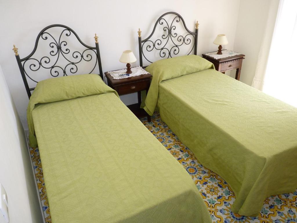 two beds with green covers in a room with two tables at Casa Fortunata in Positano