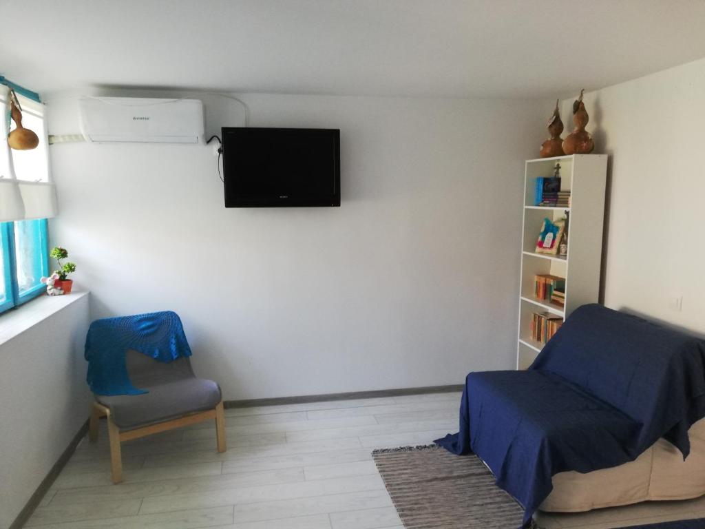 a bedroom with a chair and a tv on the wall at Casa Batranului Pescar - Old Fisherman's House in Jurilovca