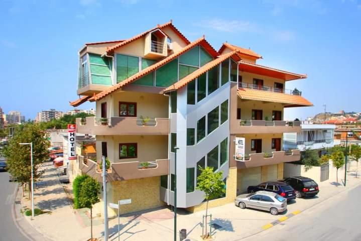 a building with cars parked in a parking lot at Hotel Colosseo in Vlorë