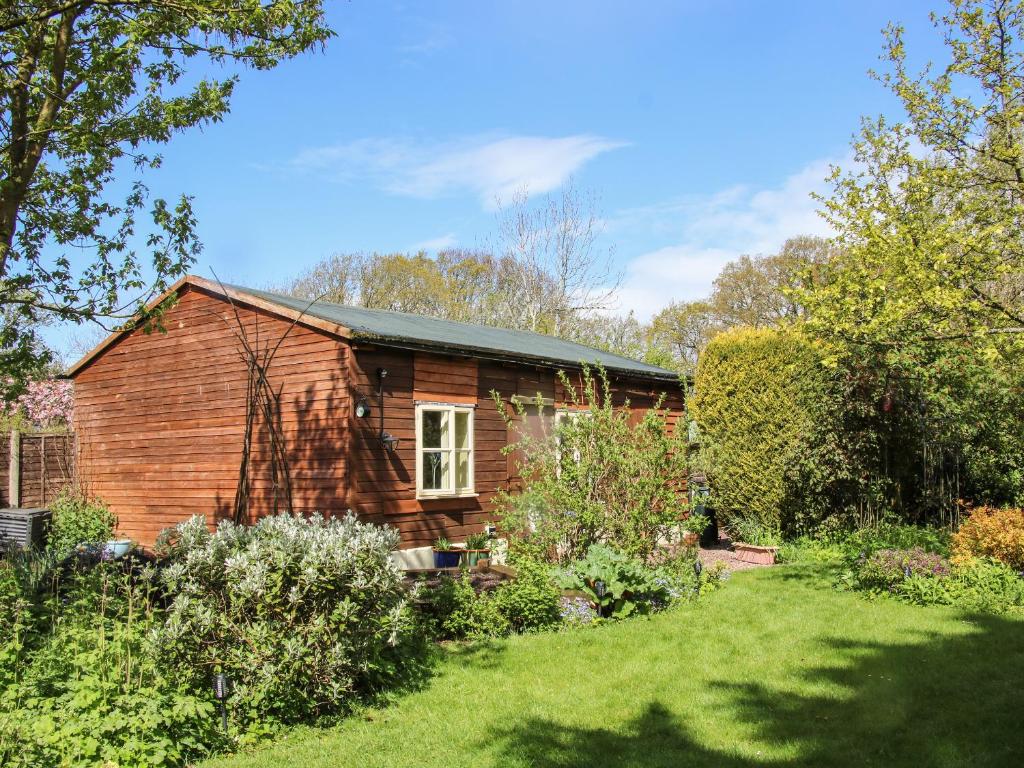 une petite maison en bois dans un jardin dans l'établissement The Garden Lodge, à Bridgnorth
