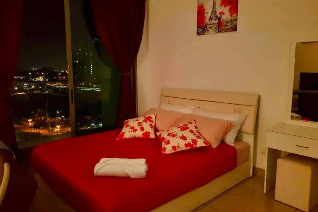 ein Schlafzimmer mit einem roten Bett mit Kissen und einem Fenster in der Unterkunft Cosy Studio Netflix SelfCheckIn Cyberjaya 1 in Cyberjaya