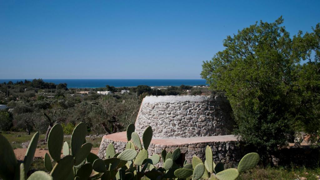 a stone building with the ocean in the background at Piccolo Trullo Salentino in Marina di Pescoluse