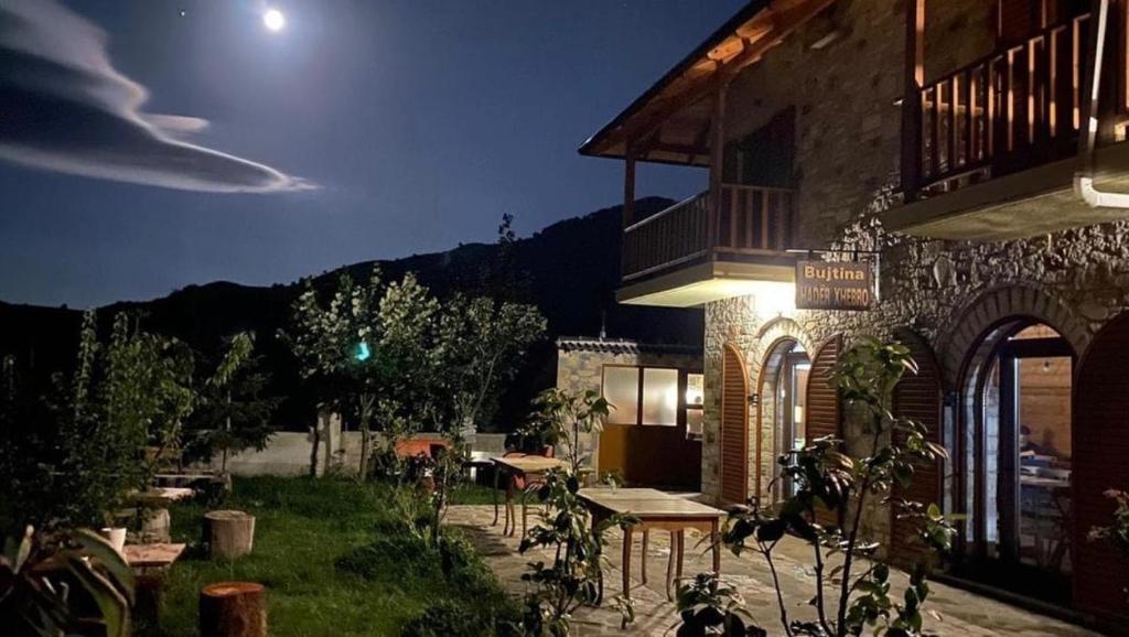 a building with a table outside of it at night at Bujtina Hadër Xhebro in Tepelenë