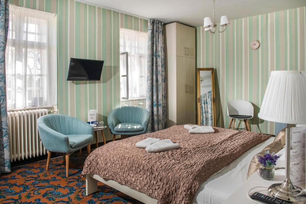 ノスヴァイにあるTündérkert Hotel Noszvajのベッドルーム1室(ベッド1台、椅子2脚、鏡付)