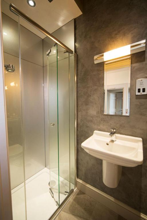 a bathroom with a sink and a glass shower at East Walls Hotel in Chichester