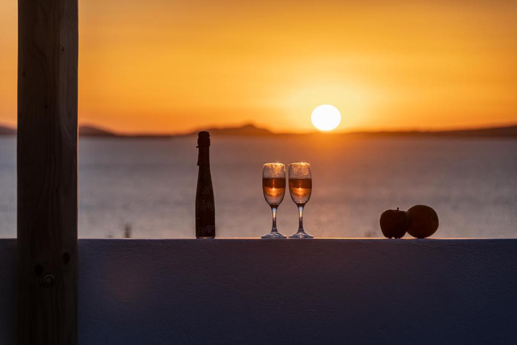 two glasses of wine sitting on a ledge with the sunset at Naxian Horizon in Naxos Chora