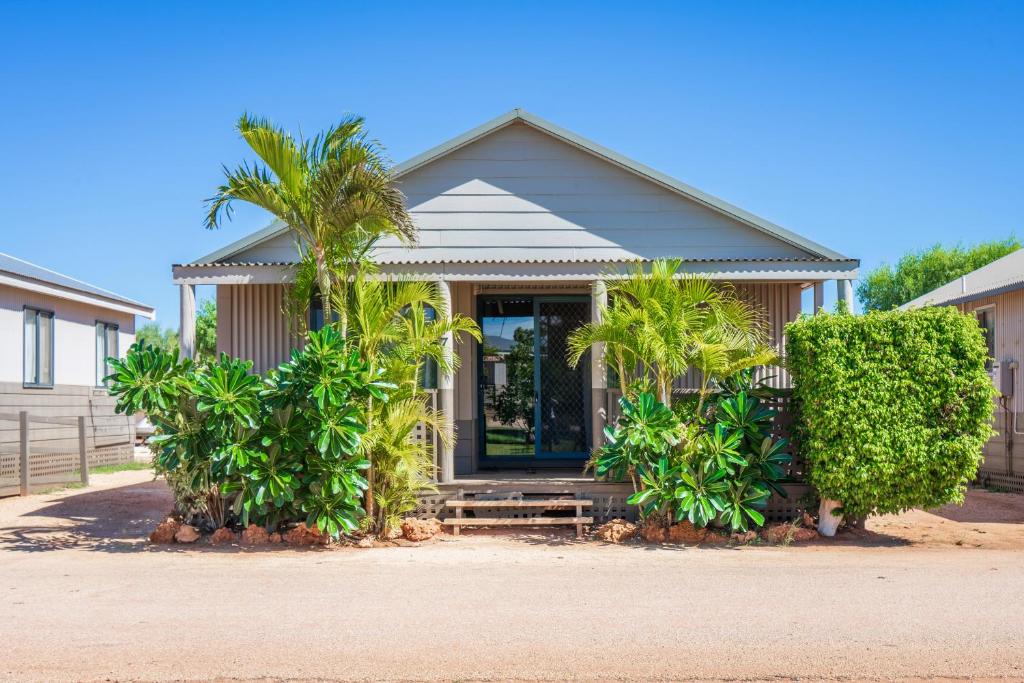 a house with palm trees in front of it at Ningaloo Caravan and Holiday Resort in Exmouth