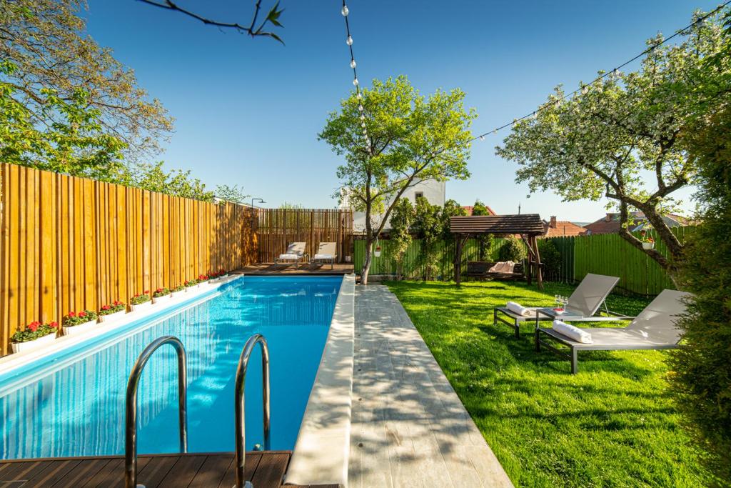 einen Pool im Hinterhof mit einem Holzzaun und Gras in der Unterkunft Casa Stella - spacious central villa in Cluj-Napoca