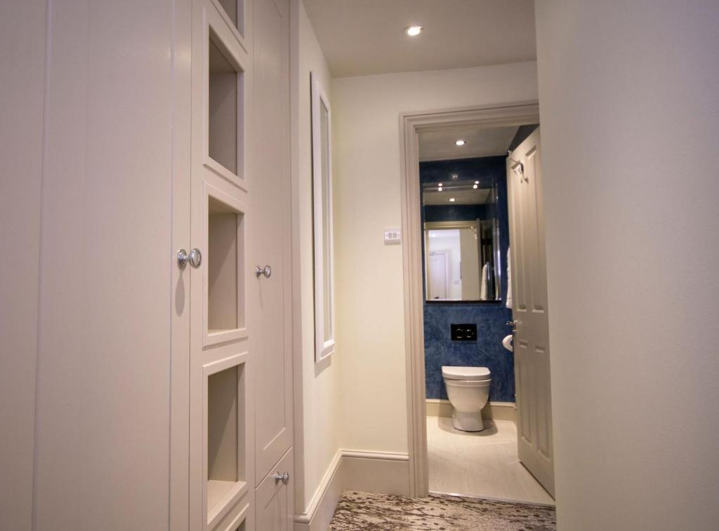 a bathroom with a toilet and a hallway with a door at East Walls Hotel in Chichester