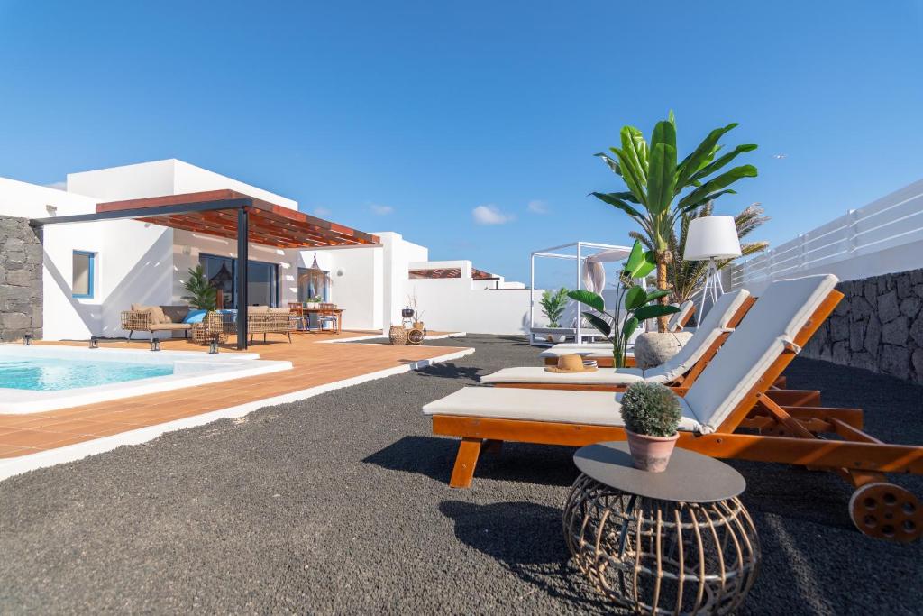 a villa with a pool and chairs and a house at Villalia Famara in Playa Blanca