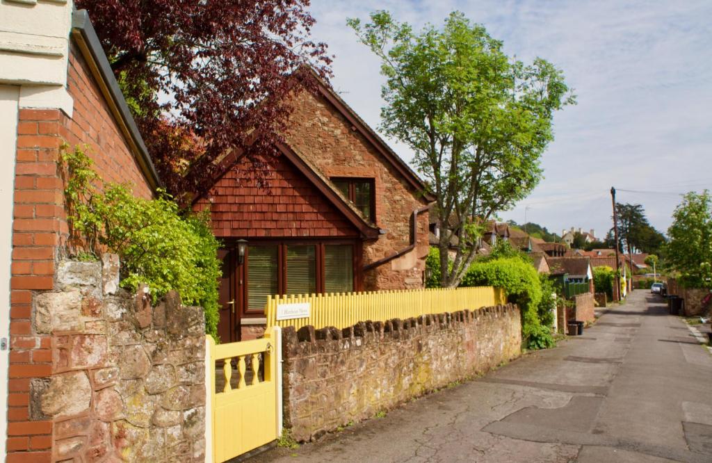 una recinzione gialla di fronte a una casa di mattoni di Minehead mews cottage a Minehead
