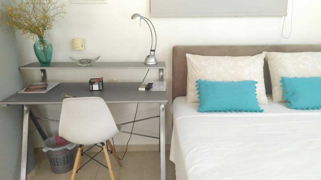 a bedroom with a desk and a bed with blue pillows at Vacations in Patra in Patra