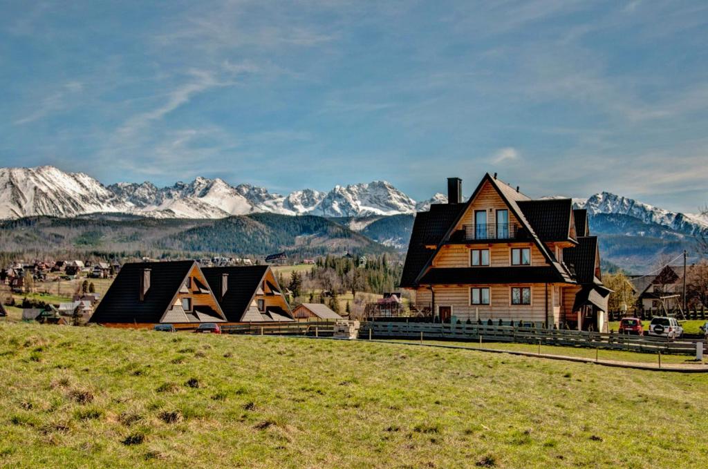 a house on a hill with mountains in the background at Widokowe Domki Gawlaki in Zakopane