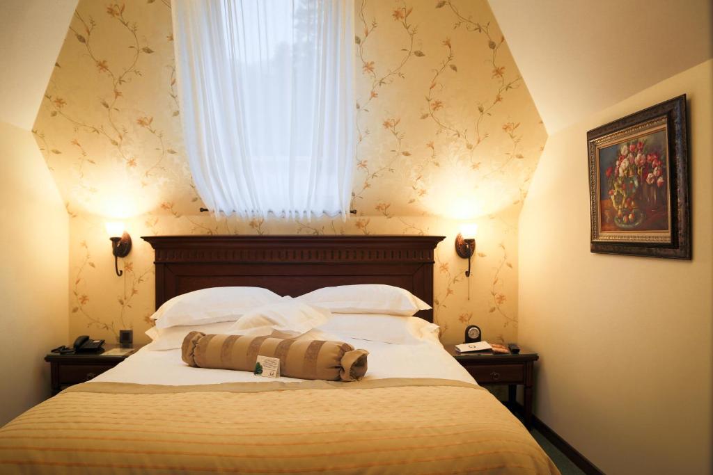 um quarto com uma cama grande e uma janela em Hotel Foisorul cu Flori em Sinaia