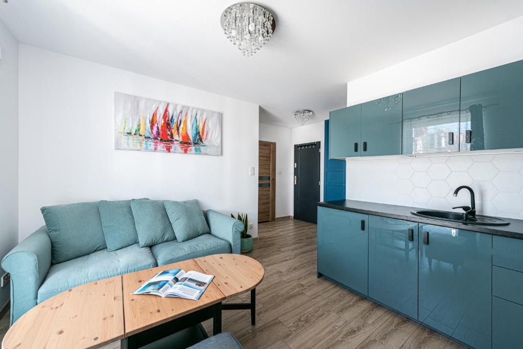 ein Wohnzimmer mit einem blauen Sofa und einem Tisch in der Unterkunft Apartament Niebieski OPTILOCUS in Danzig