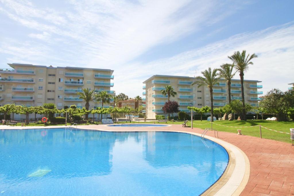 a large blue swimming pool with buildings in the background at Alea Rentals - Los Juncos in La Pineda
