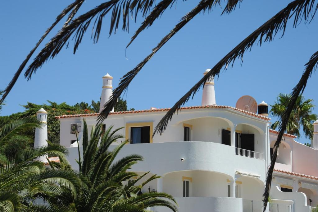 a white house with palm trees in front of it at Renovated Vale do Milho Golf Apartment with sea view in Carvoeiro