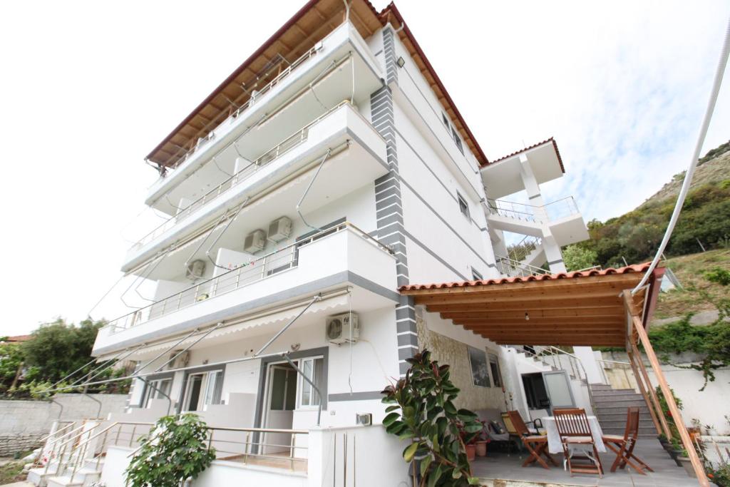 a white house with a balcony and chairs at Hotel Erviliano in Borsh