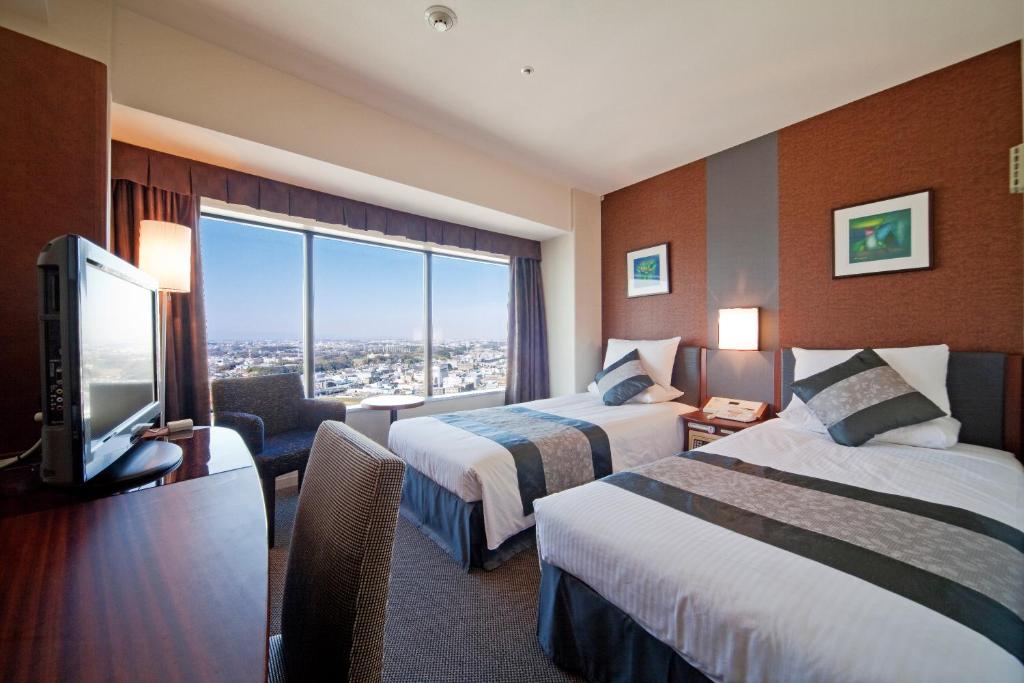 a hotel room with two beds and a flat screen tv at Shin Yokohama Prince Hotel in Yokohama