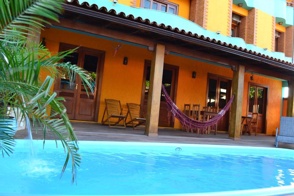 a house with a hammock in front of a pool at Pousada Maravista in Anchieta