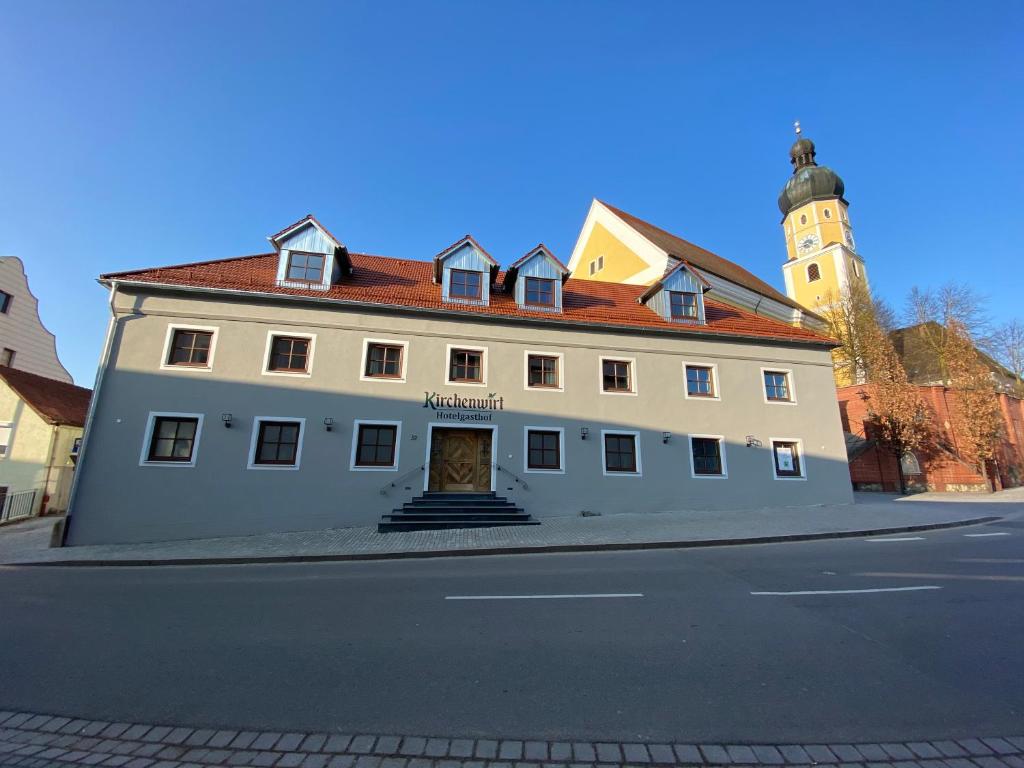 a large white building with a clock tower at Hotelgasthof Kirchenwirt in Schierling