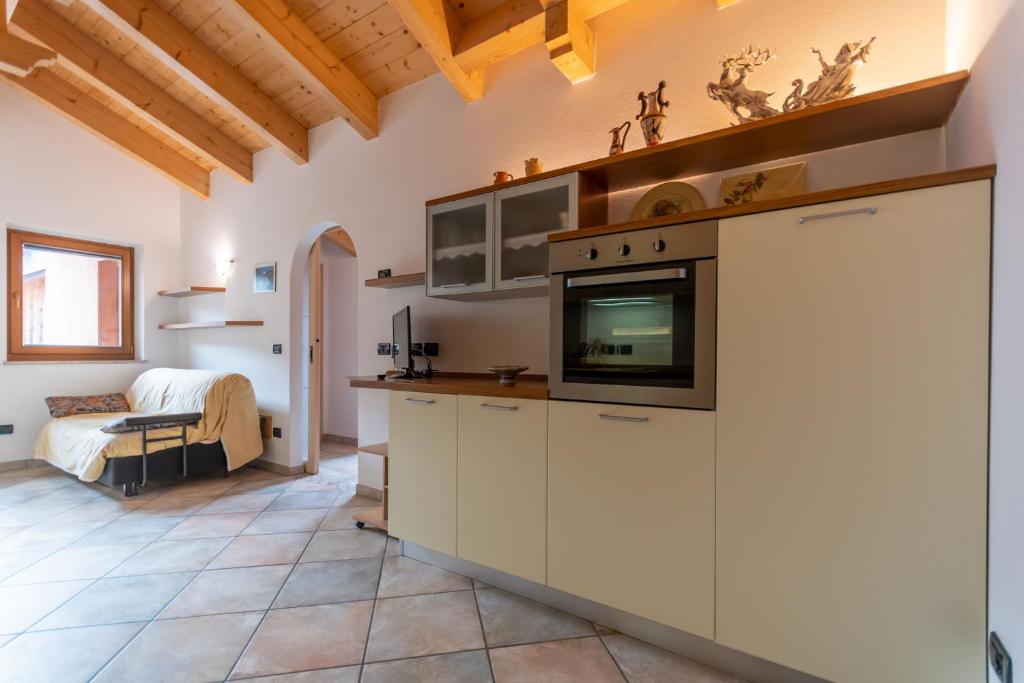a kitchen with white cabinets and a bed in a room at Casa Sartori in Pozza di Fassa