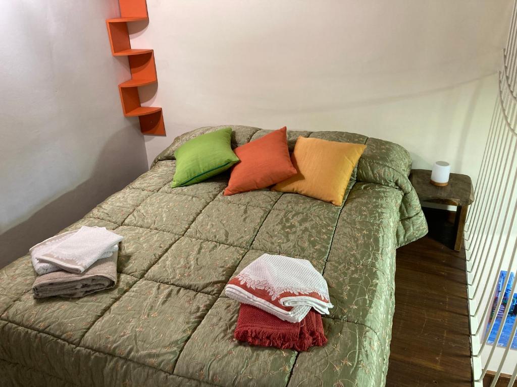 una cama con almohadas coloridas en una habitación en La casetta nel granaio, en Capranica