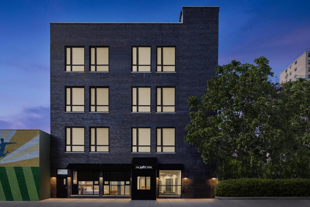 a black brick building with a tree in front of it at The Baltic Hotel in Brooklyn