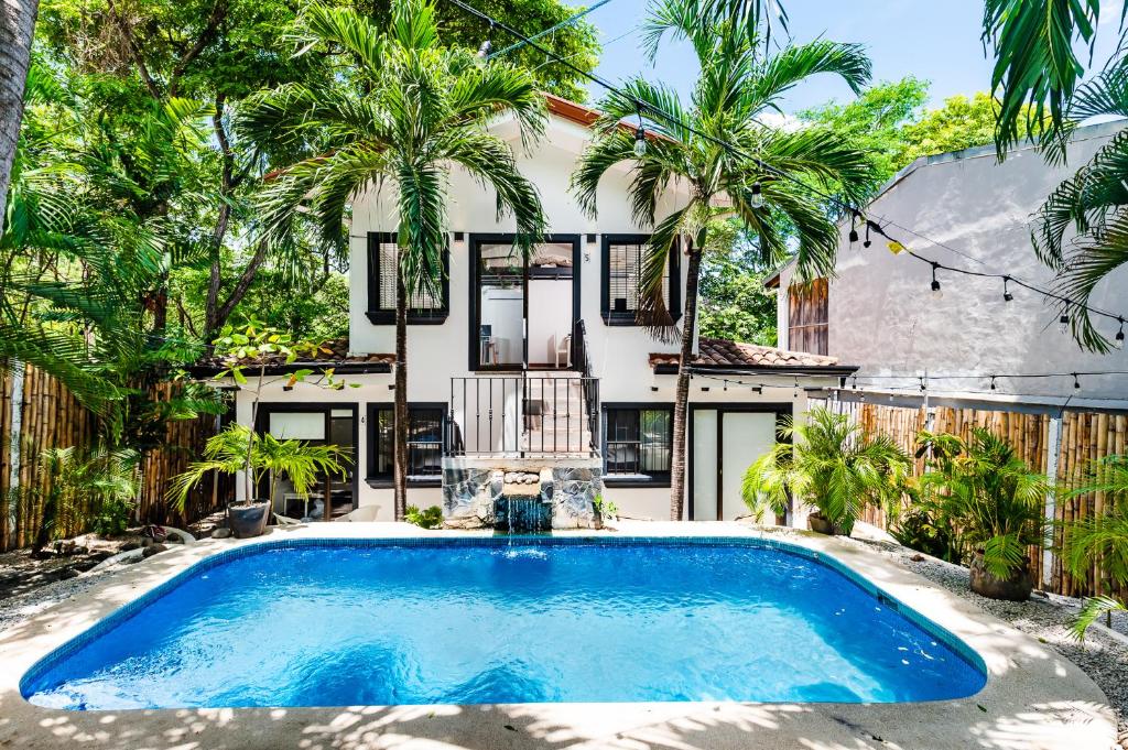 una piscina frente a una casa con palmeras en Hotel Gardenia Tamarindo, en Tamarindo