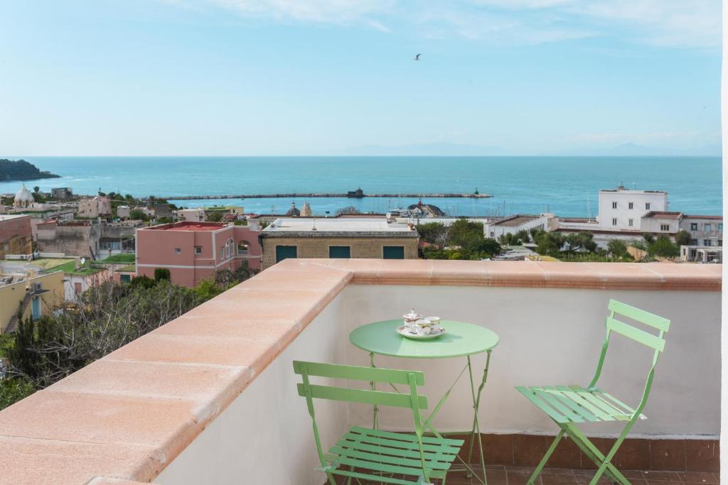 una mesa verde y 2 sillas en un balcón con vistas al océano en Terramare Guesthouse, en Procida