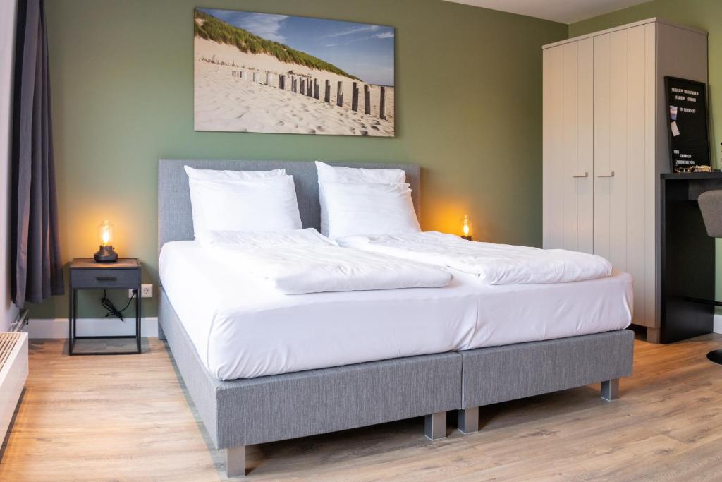 um quarto com uma cama grande e lençóis brancos em Studio 23 em Zandvoort