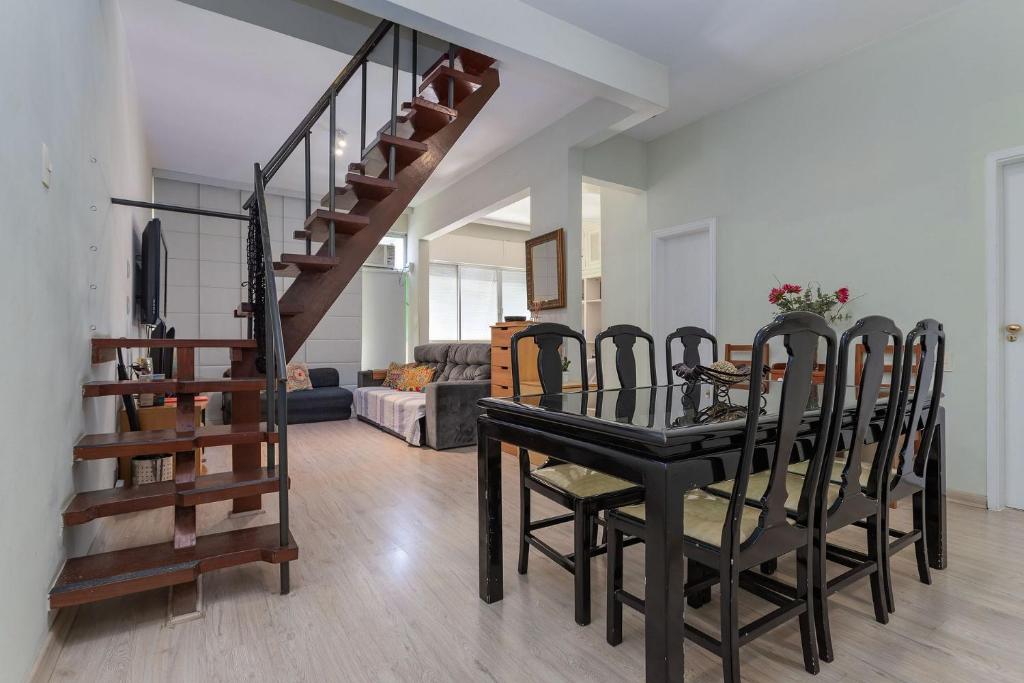 a dining room with a table and chairs and a staircase at Duplex a pé praia de Ipanema com wifi e lavanderia in Rio de Janeiro